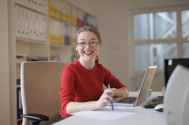 mulher sorrindo sentada na frente de um computador