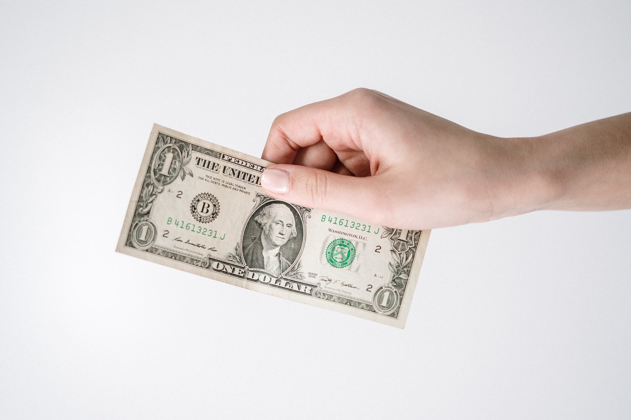 uma mão segurando uma nota um dólar