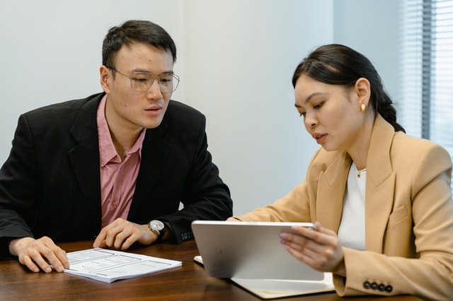 um homem e uma mulher conversando olhando para um tablet