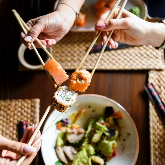 imagem de três pessoas segurando um sushi