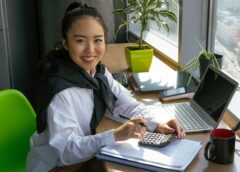 imagem de jovem asiática com uma calculadora em frente ao notebook