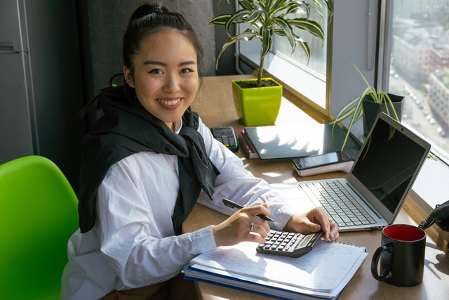imagem de jovem asiática com uma calculadora em frente ao notebook
