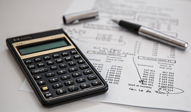 Imagem de calculadora financeira junto com documentos financeiros