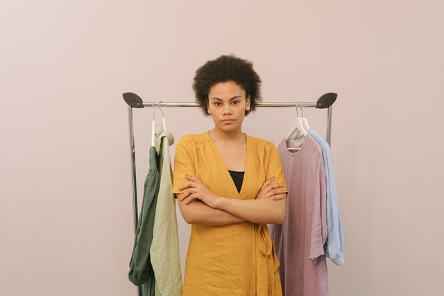 Imagem de empreendedora em frente a uma arara de roupas