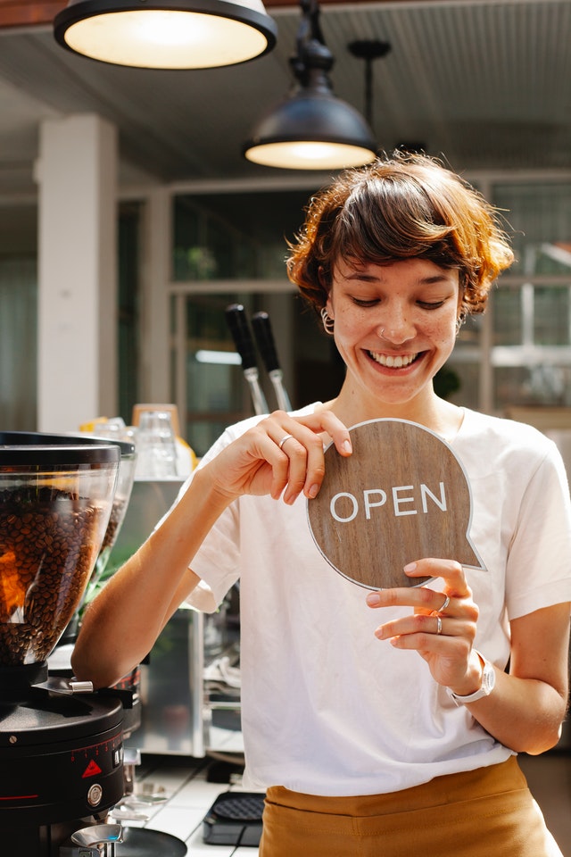Imagem de uma mulher de negócios com a placa de "aberto"